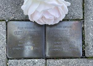 zwei Stolpersteine mit weißer Rose