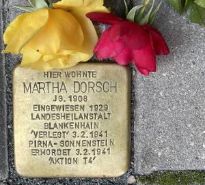 Stolperstein mit roter und gelber Rose