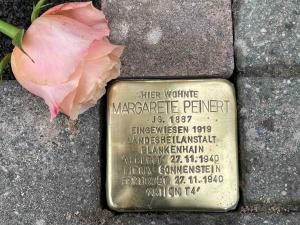 Stolperstein mit rosafarbener Rose