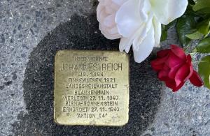 Stolperstein mit weißer und roter Rose